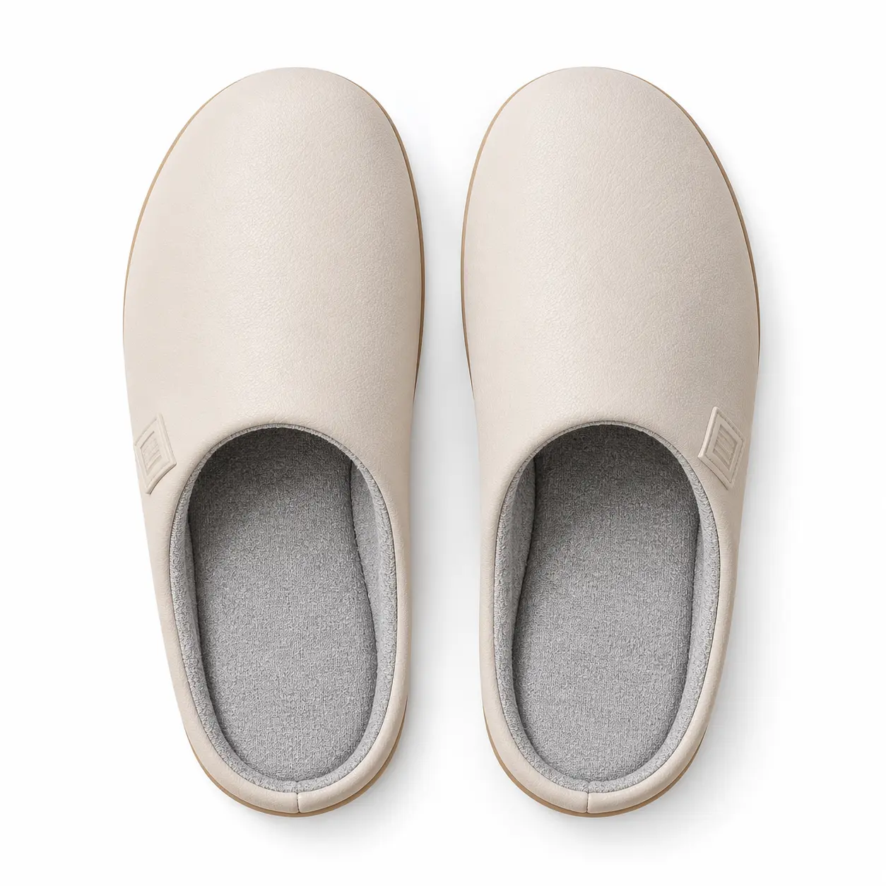Chaussons beiges vus du dessus, avec avant arrondi fermé et intérieur textile gris visible.