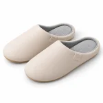Paire de chaussons homme beiges en synthétique PU, avec intérieur gris et talon ouvert, sur fond blanc.