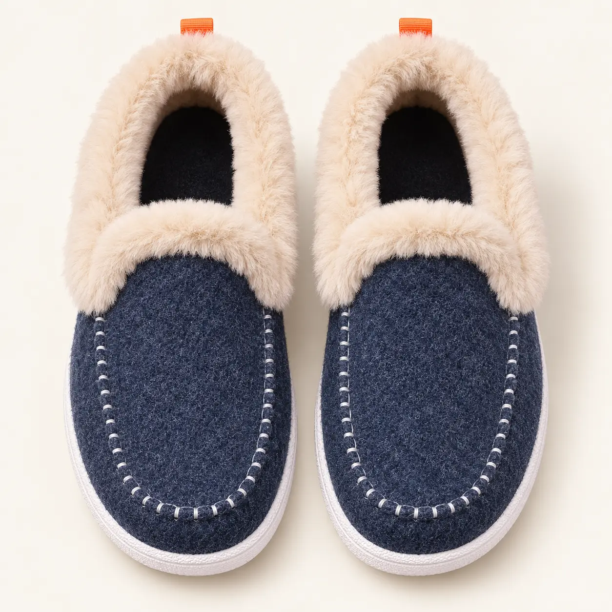 Chaussons bleu marine vus du dessus, avec col beige, intérieur sombre et coutures autour de l’avant du pied.